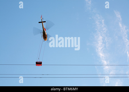 Carrying out National Gridoverhead high voltage electricity power line maintenance work repairs using a cradle hanging from a helicopter. England, UK Stock Photo