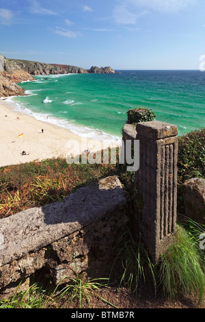 A wall and pillar provide foreground interest in this view over Porthcurno beach towards Treen beach and Logan Rock, Cornwall Stock Photo