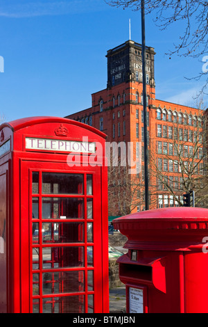 Red K6 UK telephone box designed by Sir Giles Gilbert Scott with pillar box and Belper North Mill Derbyshire in background Stock Photo