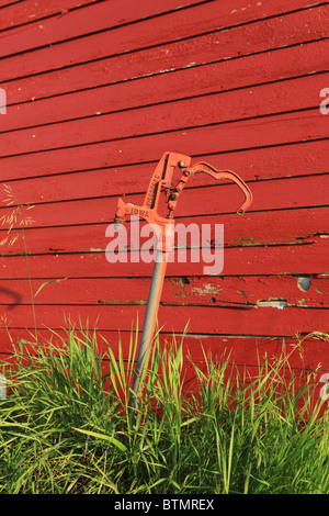 Water hydrant in Iowa in front of red corn crib barn Stock Photo