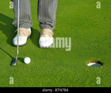 Golf green hole course man putting ball inside short putt Stock Photo