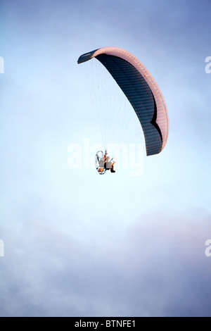 A powered para glider flying overhead at sunset. Stock Photo