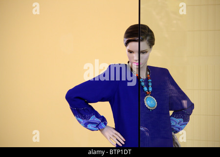 Shop mannequin posing wearing a blue suit with glass in front of her Stock Photo