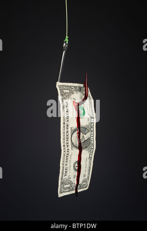 A bleeding dollar bill on a stainless steel fish hook against a slight gray gradient backdrop. Stock Photo