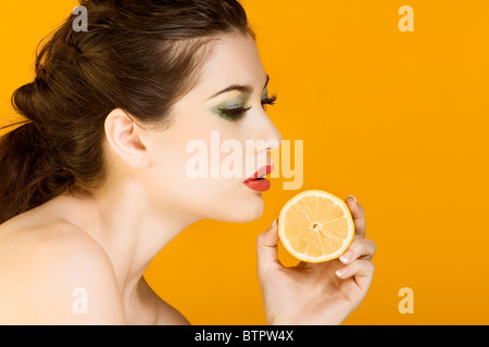 Gorgeous young woman wearing colorful make-up and holding slice of lemon Stock Photo