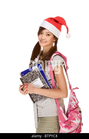 Asian school girl wearing red Santa Claus hat with backpack holding Composition book, notebooks and pen Stock Photo