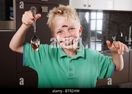 Boy in kitchen with cake mix on his face