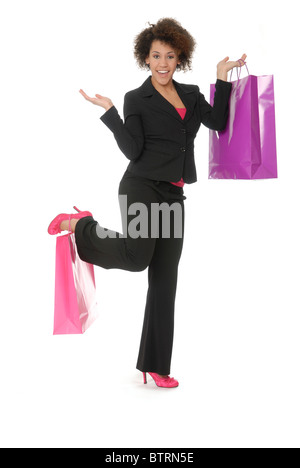 Attractive, enthusiastic young woman shopper, holding one bag in her hand and one on her shoe or foot. Model is mixed raced. Stock Photo