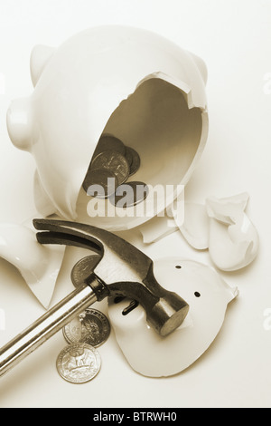 Pieces of broken piggy bank with scattered coins and hammer Stock Photo