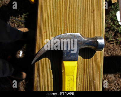 claw hammer construction building yellow head metal handle on wood closeup shadow stud Stock Photo