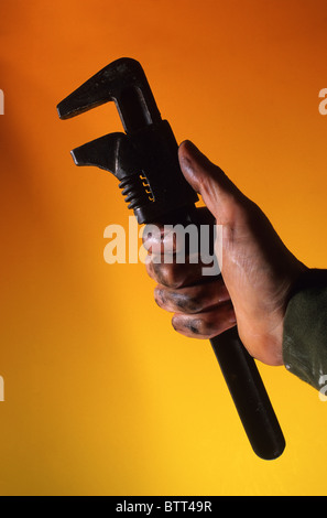 mechanic with oily hand holding adjustable spanner Stock Photo