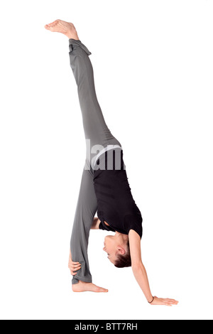 Young fit woman doing Standing Split yoga asana (Sanskrit name: Urdhva Prasarita Eka Padasana), isolated on white background. Stock Photo