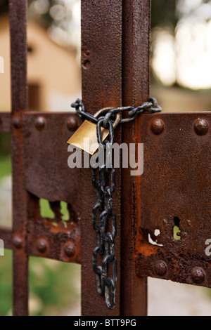 Old rusty gate locked with chain and new lock, close up, Italy, Tuscany Stock Photo