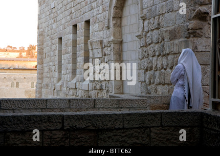 Jewish man covered with talit stands in the old city of Jerusalem and prays in the direction of the Wailing Wall at Yom Kippur Stock Photo