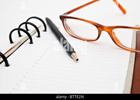 Pen and glasses lying on opened notebook Stock Photo