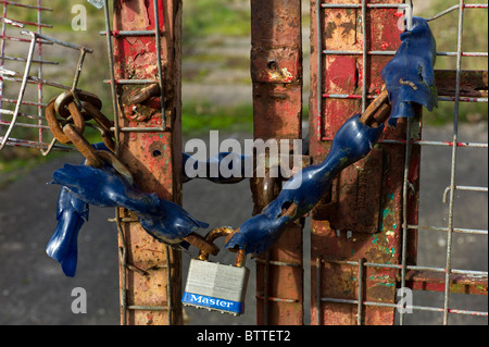 A chained up entrance gate to the wasteland site of a bankrupt business in the recession Stock Photo