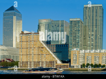 The skyline of Canary Wharf on the Isle of Dogs in London, with a Thames Clipper river bus passing along the River Thames Stock Photo