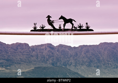 Wrought iron ranch sign at gate near Presidio, Texas, USA with Sierra Grande massif across Rio Grande in Mexico in distance Stock Photo