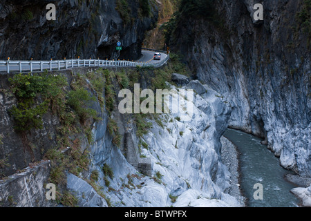 Cliffside road under rock overhang and stream flowing through marble canyons, East-West Central Cross-Island Highway, Taroko National Park, Taiwan Stock Photo