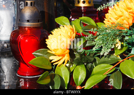 Red candles and artificial flowers on a grave Stock Photo