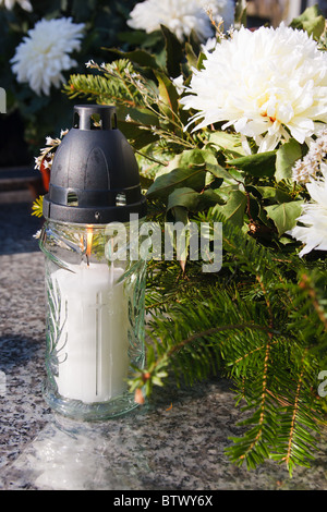 White candle and artificial flowers on a grave Stock Photo