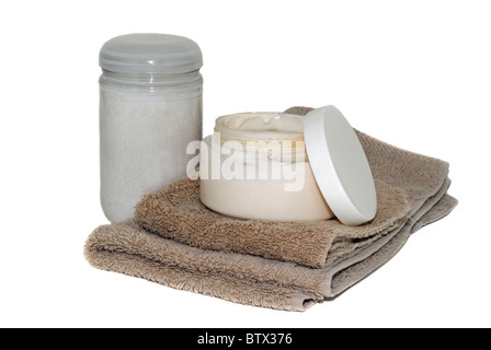 An open jar of facial cream and a bottle of bath beads with a wash rag and hand towel. Stock Photo