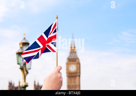 Hand holding Union Jack flag with Big Ben in the background. London, England. Stock Photo