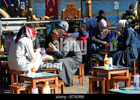 ISTANBUL, TURKEY. Turkish girls eating balik ekmek (fish sandwiches) by the ferry terminal in Eminonu district. 2010. Stock Photo