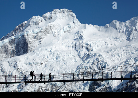 Family of hikers on Hooker River Footbridge & Mt Sefton, Aoraki / Mt Cook National Park, Canterbury, South Island, New Zealand Stock Photo