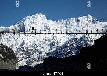 Hiker on Hooker River Footbridge & Mt Sefton, Aoraki / Mt Cook National Park, Canterbury, South Island, New Zealand Stock Photo