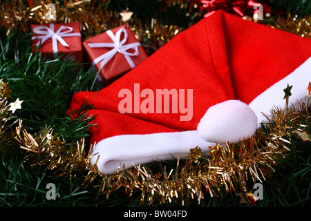 Red Santa's hat placed on green fir with yellow decoration chain Stock Photo