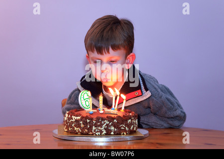 A 6 year old boy blowing out the candles on his birthday cake Stock Photo