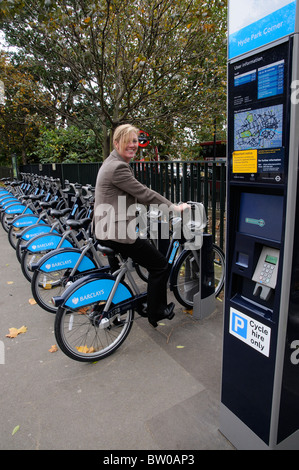 Female commuter collecting a hire bicycle in central London UK Stock Photo