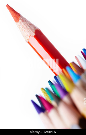 Image of red crayon surrounded by several rows of colorful pencils Stock Photo