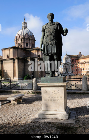 Bronze statue of Julius Caesar with Foro Romano behind, Fori Imperiali Stock Photo