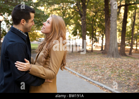 A young couple embrace in New York's Central Park. She looks skyward. Stock Photo