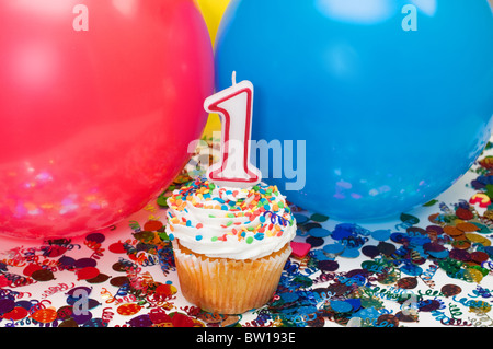 Celebration with balloons, confetti, cupcake, and number 1 candle. Stock Photo