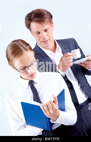 Portrait of busy female making notes with curious man behind Stock Photo