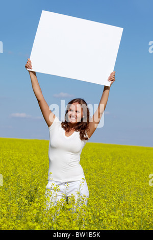 Portrait of charming girl with blank paper standing in the field Stock Photo