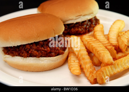 Two sloppy joe burgers and crinkle cut french fries isolated on black background. Stock Photo