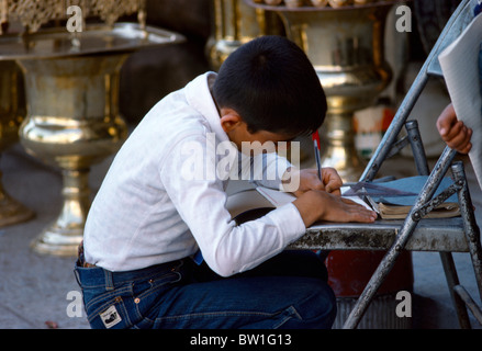 Isfahan Iran Shop Owner's Son Doing Homework using a Chair as a Desk In the Street Stock Photo