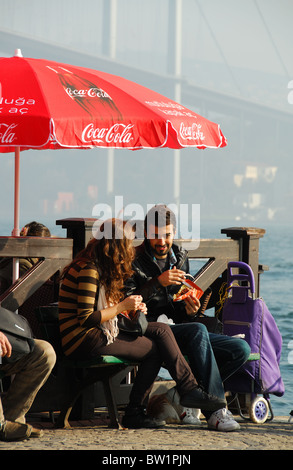 ISTANBUL, TURKEY. A young Turkish couple eating takeaway food by the Bosphorus at Ortakoy market, Besiktas district. 2010. Stock Photo