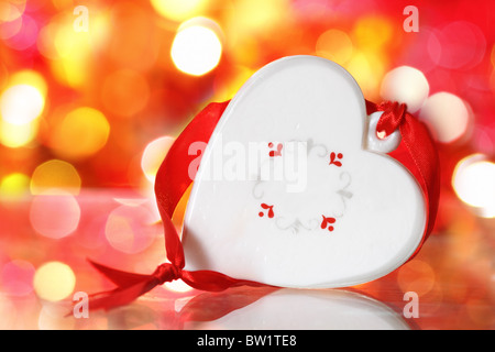 Christmas white heart with red ribbon against blurred background Stock Photo