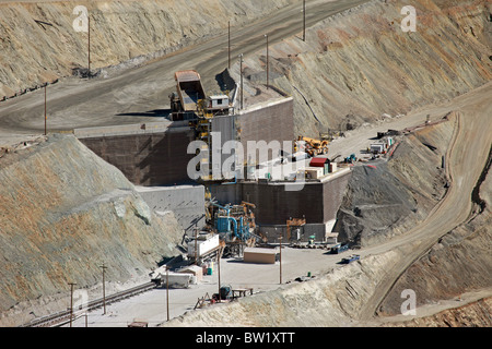 Large mine truck dumping ore into rock crusher from overhead. Kennecott Copper Mine. Heavy industrial work. Stock Photo