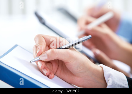 Image of human hand writing on paper at seminar or conference Stock Photo