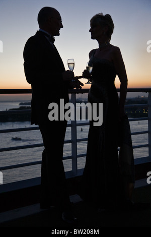 Romantic couple sharing a tender moment drinking champagne together toasting  sailing away from port in Venice, Italy at dusk Stock Photo