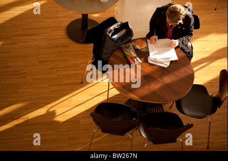 Overhead view looking down on a student working writing sitting at a table in the cafe of Aberystwyth University Wales UK Stock Photo