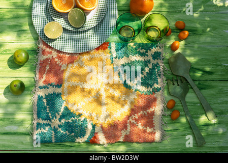 Still-Life of small hand-made citrus fruit-patterned rug with oranges and limes Stock Photo
