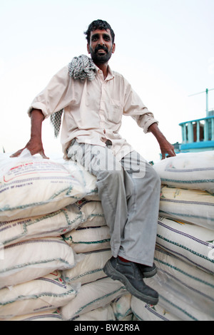 A man sitting on stacked sacks at the port, Dubai, United Arab Emirates Stock Photo