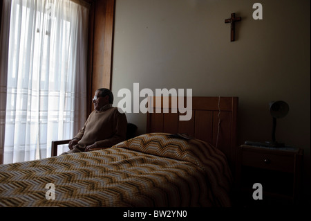 Senior citizen sitting by the window alone in his bedroom Stock Photo
